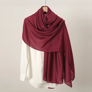 Détail d'une écharpe en lin rouge foncé drapée élégamment sur une chemise blanche