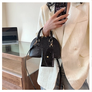 Detail of black crocodile embossed shell bag with gold hardware and small hanging coin pouch