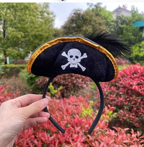 Detailed view of Halloween pirate headband with golden trim, skull print and black feathers