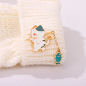 Primo piano della spilla gatto che pesca con catena d'oro su maglione bianco