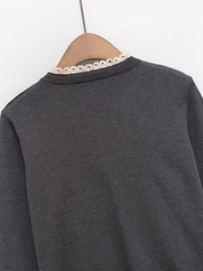 Détail d'un pull en maille gris foncé avec col en dentelle vintage sur cintre en bois