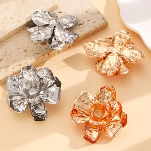 Macro shot of oversized wrinkled metal leaf earrings in gold, silver, and rose gold