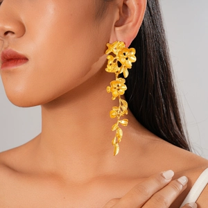 Détails de boucles d'oreilles pendantes fleurs dorées sur mannequin, fini métallique