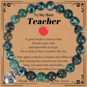 Close-up of a teacher appreciation stone bracelet with a silver apple charm on a card
