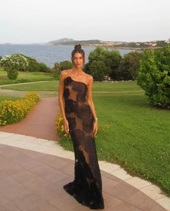 Detail of elegant black one-shoulder evening gown featuring textured rose burnout patterns