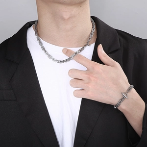 Detail view of silver stainless steel chain necklace and bracelet set with OT buckle on model