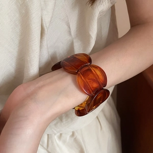Detailed close-up of dark amber resin links on an acrylic bracelet with vintage textures