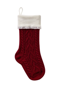 Detail of red cable-knit Christmas stocking featuring ivory faux fur trim and tassels
