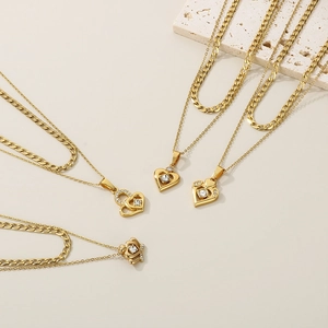 Layered gold heart pendant necklace featuring sparkling crystals on a textured stone base