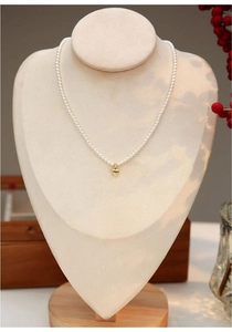 Detail of freshwater baby pearls with a 14K gold heart pendant on a jewelry display