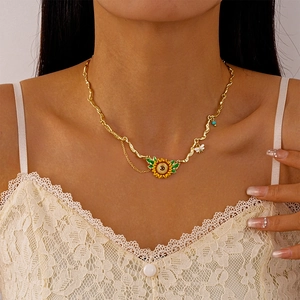 Detail of sunflower and bee pendant on irregular gold chain with asymmetric link design