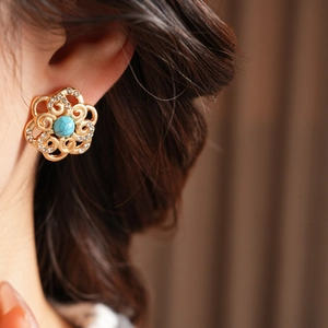 Close-up of vintage gold flower earrings with turquoise stone and diamond accents