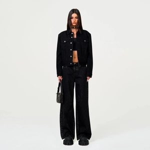 Détail du pantalon en jean noir à taille haute et jambe large avec texture élégante