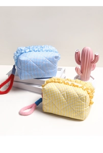 Quilted plaid makeup bags with ruffled edges and colorful fuzzy loops in blue and yellow