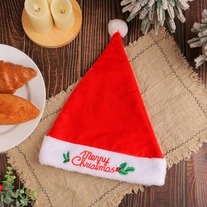 Classic red velvet Santa hat with Merry Christmas embroidery on a rustic wooden table