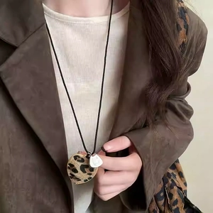 Leopard print heart pendant necklace on a black braided rope worn by a model