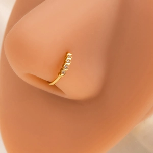 Close-up of golden leaf nose ring with four white zircons on a silicone nose model