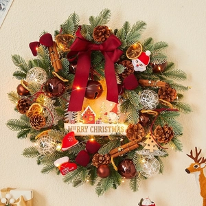 Christmas wreath with red bow, pine cones, and LED lights on a white wall decoration