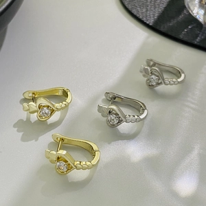Macro shot of gold and silver heart-shaped earrings with sparkling cubic zirconia stones