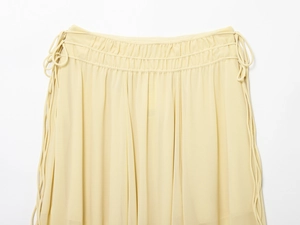 Detail of light yellow chiffon skirt featuring elastic ruched waist and side drawstrings