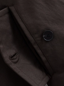 Vista macro della trama del tessuto twill e del bottone scuro su un cappotto trench