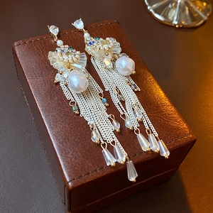 Macro view of long tassel earrings with irregular pearls and crystals on leather box
