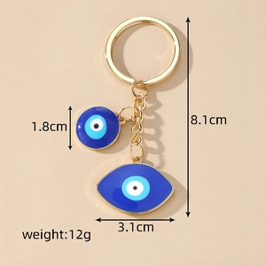 Detail view of gold evil eye keychain with blue enamel pendants showing dimensions and weight