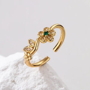 Macro shot of gold-plated flower ring with green zircon and crystals on a white rock