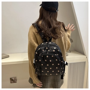 Close-up of a black mini backpack with pink floral pattern and front zipper pocket