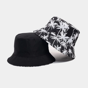 Dual-sided bucket hat featuring solid black and tropical palm tree print for summer sun protection