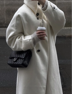 Detail of minimalist beige long wool coat with premium buttons and textured fabric