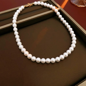 Détail de perles blanches rondes avec fermoir doré sur plateau à bijoux noir
