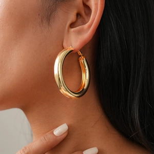 Macro shot of thick gold hoop earrings with a mirror polished finish on model