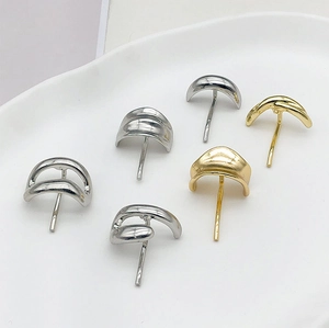 Close-up of gold and silver metallic curved earrings displayed on a white tray