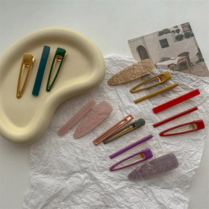 Set of colorful matte and marble hair clips displayed on a stylish beige tray