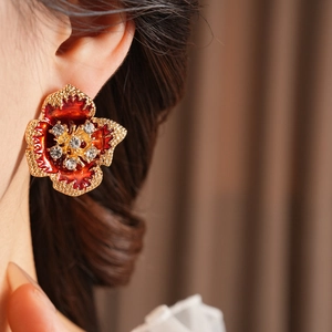 Close-up of vintage red enamel flower earrings with gold edges and sparkling crystals