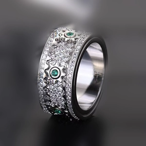 Macro detail of mechanical gear ring featuring sparkling pavé crystals and green emeralds