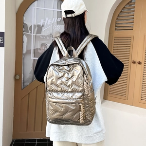 Gesteppter metallischer Rucksack in Champagnergold, von einem Model im Freien getragen