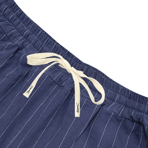 Detailed close-up of elastic waistband with white drawstring on blue striped linen shorts