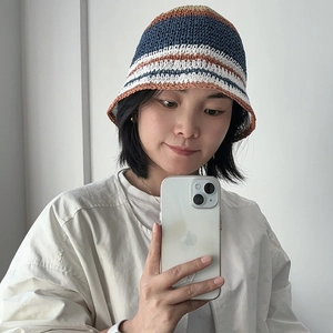 Stylish woman wearing a striped hand-woven straw bucket hat for summer sun protection