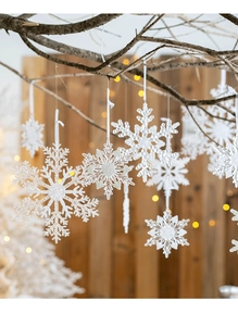 Detail of clear acrylic snowflake ornaments hanging with warm festive string lights