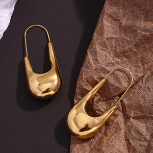 Vue détaillée de boucles d'oreilles épingle à nourrice dorées au fini poli sur fond mat