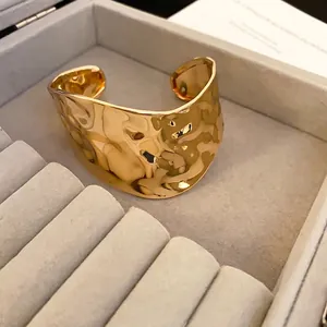 Irregular wide open bangle with hammered gold finish texture in a jewelry box