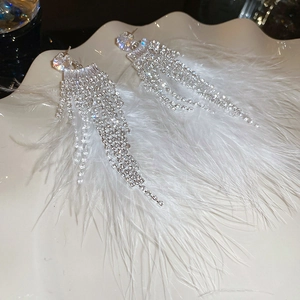 Detailed view of long white feather tassel earrings with sparkling rhinestones on tray