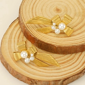 Elegant gold shell earrings with white pearls on natural wood display stand