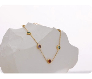 Detail of a gold titanium steel necklace with colorful gemstones on a white stone base