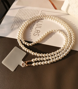 Detail view of handmade white pearl phone strap with gold metal clasp and connector tab