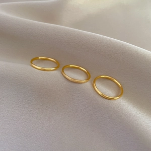 Close-up of three minimalist gold stackable rings in polished and matte titanium steel