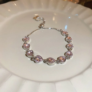 Detail of pink heart crystal bracelet with adjustable silver sliding buckle on a ceramic plate