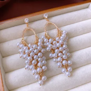 Elegant gold drop earrings with zircon studs and white pearl tassels in a velvet box